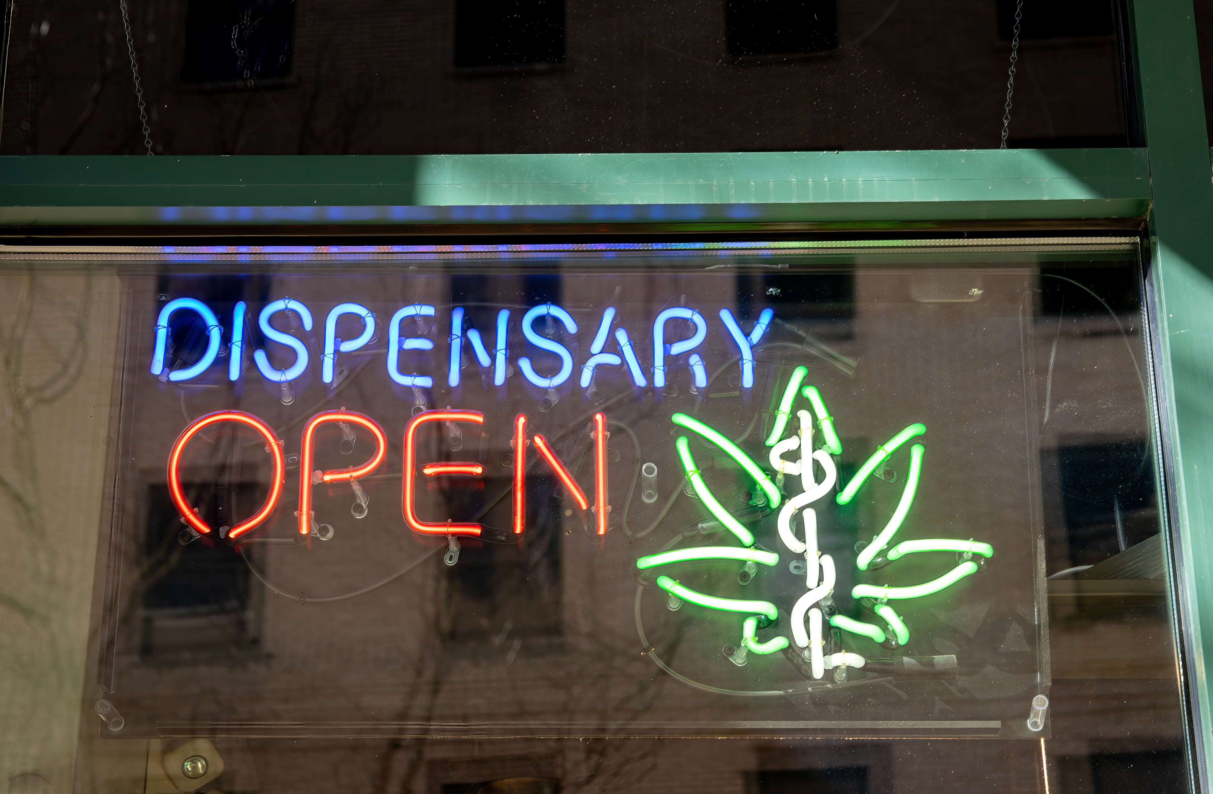 Neon sign advertising legal, medical marijuana dispensary in store window.